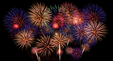 Fototapeta premium Colorful Fireworks Bursting in the Night Sky in Red, Blue, and Gold