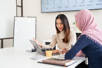 Discussion with colleague. Beautiful asian businesswoman wearing hijab while working at open space or office. Concept of occupation, freedom in business area, leadership, success, .
