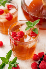 Iced raspberry tea with mint and fresh berries in glass