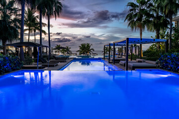 Blue lit infinity pool at sunset at a beach resort