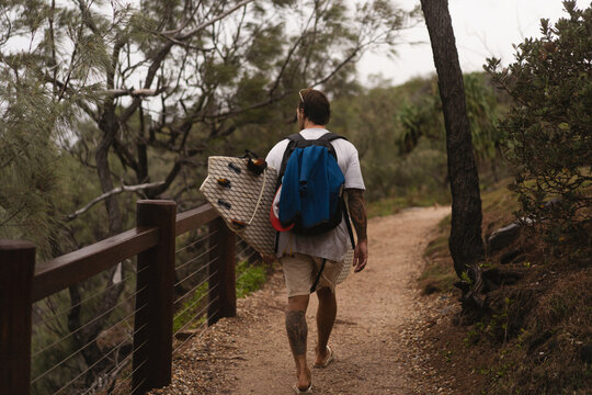 Young man carrying surfboard and walking to beach