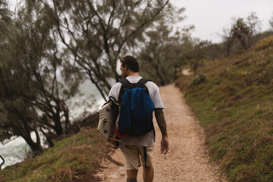 Man walks towards the beach with a surfboard