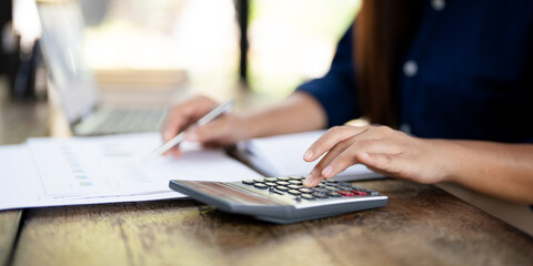 Close up woman hand using calculator to calculate home finance, accounting on table, budget management. Doing finance, budgeting and tax calculation, monthly expenses