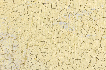 Close-up view of cracked yellow paint revealing a textured surface