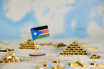 South Sudan flag on a world map with shimmering gold bars, symbolizing the nation's economic...
