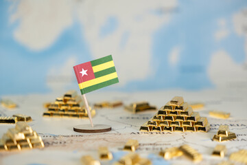 Togo's national flag stands proudly on a world map amidst numerous golden bars, illustrating the...