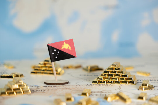Papua New Guinea flag prominently displayed alongside gleaming gold bars on a detailed world map, symbolizing global resource wealth and international economic investment opportunities - Powered by Adobe