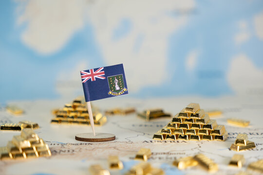 British Virgin Islands flag pin stands among scattered gold bar stacks on a world map, symbolizing offshore finance and global wealth management concepts with ample copy space