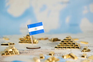 Nicaraguan flag and miniature gold bars scattered across a world map, symbolizing global finance,...