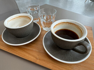 Two americano coffee cups with water served on grey table