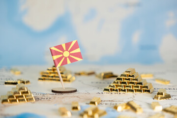 North Macedonia flag stands on a map with gold bar stacks, symbolizing national wealth, economic...