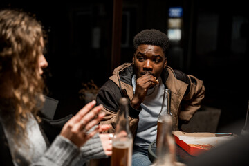 Obraz premium Friends share stories and snacks during a late-night gathering in a cozy outdoor setting