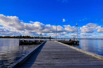 Obraz premium Wooden pier stretching into a calm body of water under a bright blue sky