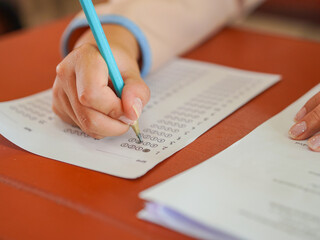 Closeup of hands female of students taking exams in a classroom, exams in school, writing and reading book. Homework and examinations in Asian. Education knowledge and learning. Concept brainstorming