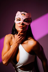 Female dancer wearing pink cat mask poses confidently in modern studio setting