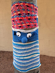 tree trunk covered in colorful crochet knitted yarn bombing