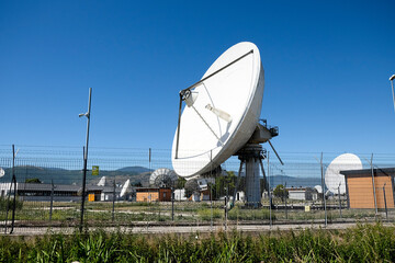 A wide shot of multiple large white satellite dishes at the Telespazio Fucino Space Centre, set...