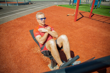 Man training on an adjustable abdominal bench. Targets core and abs. Outdoor workout improves core strength, balance, and physical control.