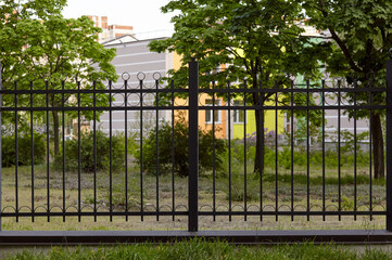 Metal fence in the city park. Decorative black iron guardrail for protection, close up