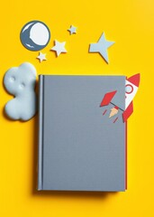 Literature for children. fantactic, fiction story. book with blank cover near cutout of rocket, stars, moon on yellow background top view mockup copy space. book mockup. 