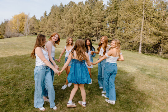 University students holding hands in a circle on campus lawn
