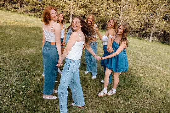 University students holding hands in a circle on campus lawn