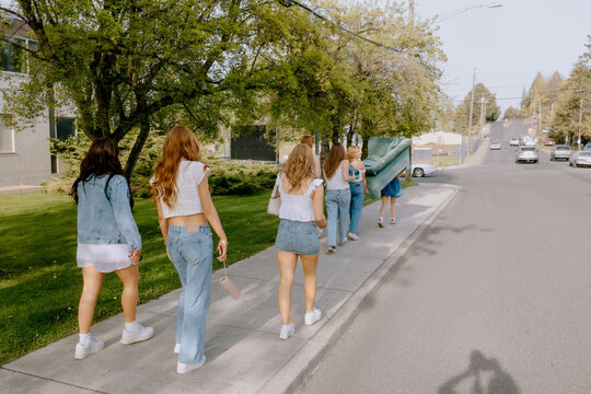 University students carrying furniture on sidewalk