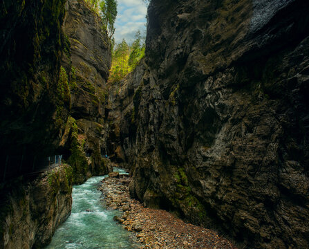 Mystical photo of Partnachklamm Gorge in Bavaria, Germany, with emerald green water, moss-covered cliffs, and atmospheric, dramatic natural scenery. vertical panorama