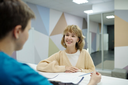 Cheerful Young Patient of Clinic at Reception Desk