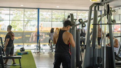 Men working out at a modern indoor gym with various fitness equipment, captured in natural daylight. Energetic atmosphere promoting health, strength, and active lifestyle in a shared workout space.