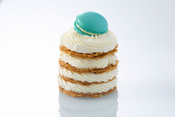 Gourmet Mille-Feuille Stack with Piped Cream and Teal Macaron Garnish on Reflective White Surface