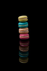 Tall Stack of Colorful French Macarons on Black Reflective Surface