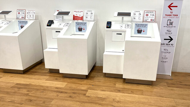 Self-service kiosks arranged in a modern retail space. The machines are sleek, predominantly white, with touch screens for user interaction.