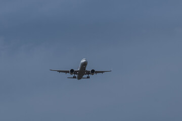 Passenger airplane flying in cloudy sky, landing gear extended