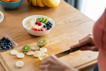 Young Asian Woman enjoying healthy cooking and enjoy eating Greek yogurt and fruits in kitchen...