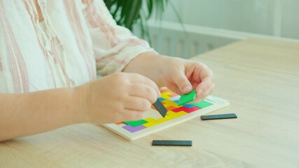 Mature female hands manipulate wooden geometric shapes intellectual puzzle, potential mental activity in preventing dementia and Alzheimer's disease, Keeping mind sharp
