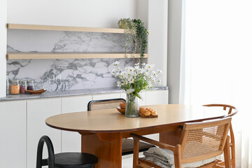 Bright peaceful modern apartment dining area featuring wooden table, chairs, and kitchen counter creating comfortable domestic space