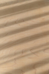 Natural warm wood texture features diagonal shadows and parallel light stripes creating an abstract background pattern on smooth brown surface. detail shows subtle wood grain of organic material