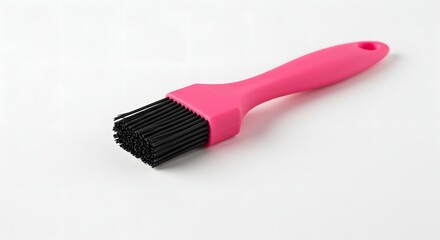 Close up of a pink handled basting brush with black bristles on a white background