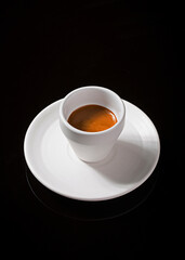 Fresh Espresso in White Cup and Saucer on Black Reflective Background