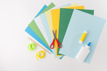 a collection of craft supplies, colorful mix of paper, scissors, a pencil, pipe cleaners, a glue...