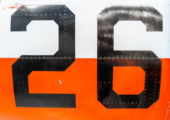 Black number -26- on an old aircraft fuselage with riveted panels