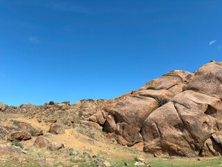 Fototapeta premium massive weathered granite boulders under vibrant blue sky in open grassland, ideal for nature blog, geology print, outdoor poster, travel branding, and background texture design