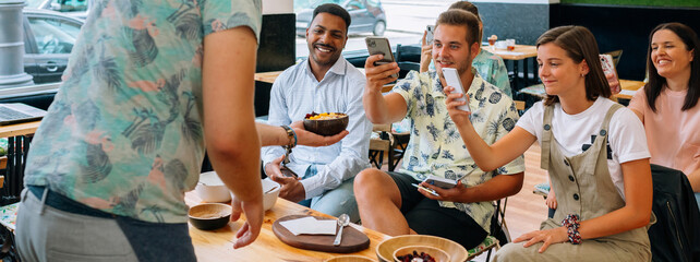 Banner of chef serving an exotic dish to food bloggers and influencers taking pictures with their smartphones during a cooking master class in restaurant. Happy audience takes photos in cook workshop.