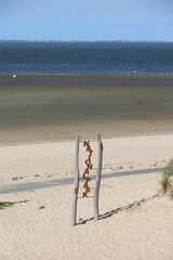 Blick auf Strand und Meer bei Gezeitenwechsel an der Nordsee in Cuxhaven mit Zeichen für...
