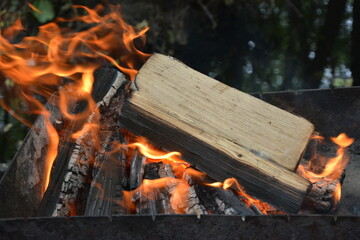 A close-up of a burning fire with logs engulfed in orange and yellow flames. The firewood is...