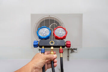 Air repair mechanic using measuring equipment for filling industrial factory air conditioners.	