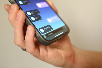 Hand holding smartphone with voice messages open in a chat app. Close-up of screen with audio...
