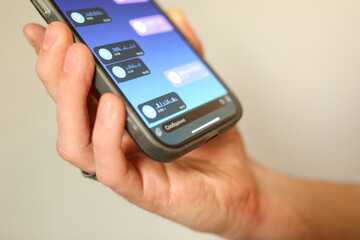 Hand holding smartphone with voice messages open in a chat app. Close-up of screen with audio...