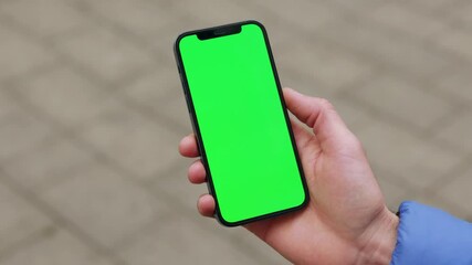 NEW YORK - December, 19 2020: Shot of hand man holding a smartphone touching phone with vertical green screen phone on background street. Message business male street device digital equipment internet - Powered by Adobe